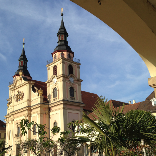 Zu sehen ist die evangelische Stadtkirche sowie einen Teil einer Außengastronomie.